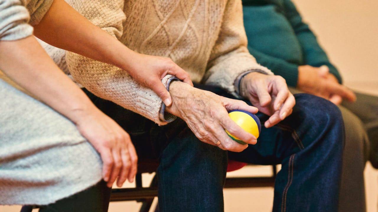 Cuidadora dando la mano a persona mayor con Alzheimer