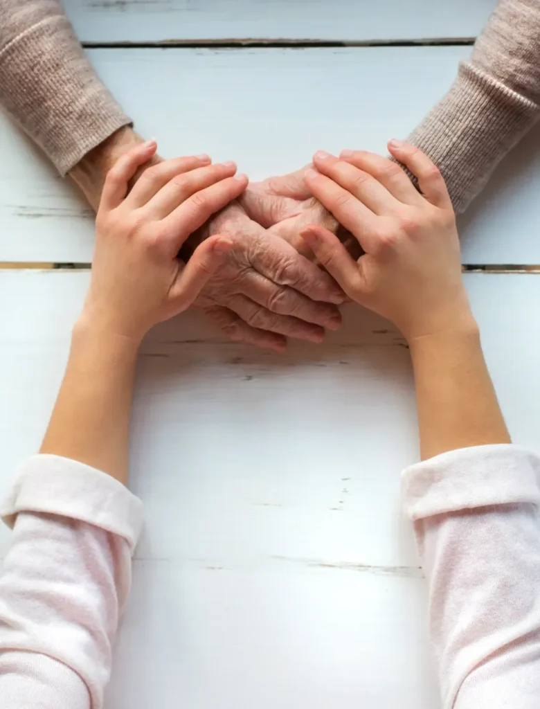 Experta en el ayuda a domicilio de personas mayores da la mano a anciana