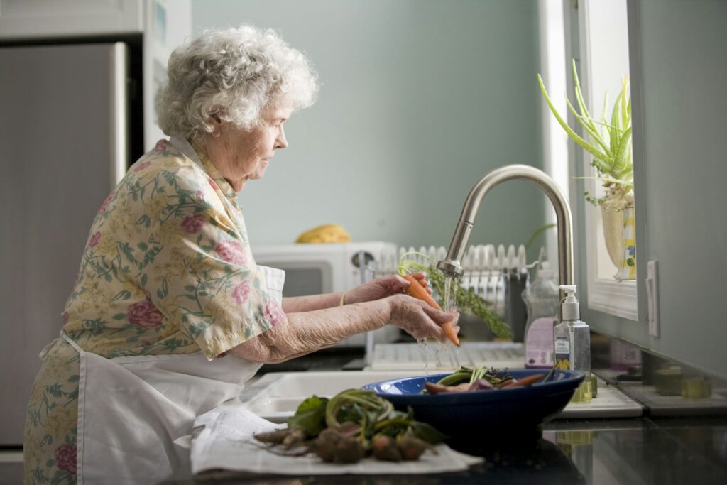Señora mayor preparando verduras en la cocina de su casa